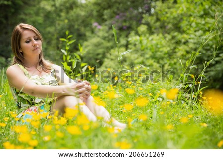 Cute young woman relaxing in field against the trees