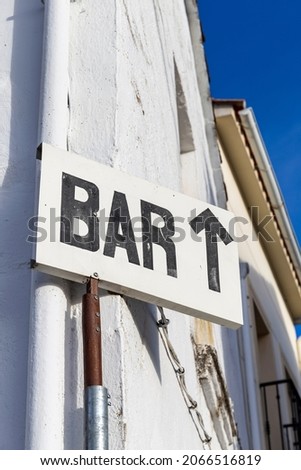 White sign with black letters of Bar with arrow on corner of old house facade. Urban rural life concept. Vertical photo and selective focus