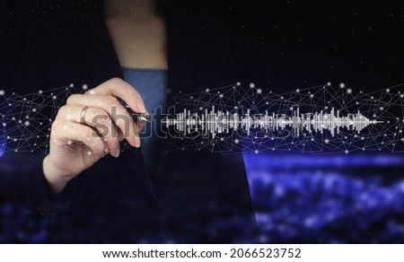 Listening to music on mobile devices. Voice recognition. Hand holding digital graphic pen and drawing digital hologram sound track, wave sign on city dark blurred background