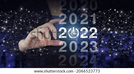 Welcome year 2022. Business new year card concept. Hand hold digital hologram 2022 sign on city dark blurred background. Concept Start New Year 2022