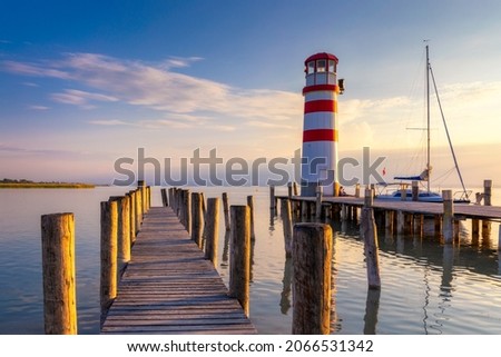 Lighthouse at Lake Neusiedl, Podersdorf am See, Burgenland, Austria. Lighthouse at sunset in Austria. Wooden pier with lighthouse in Podersdorf on lake Neusiedl in Austria. Royalty-Free Stock Photo #2066531342