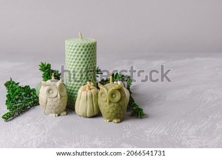Natural green beeswax candles of different shapes on gray background. Space for text. Hobby candle making