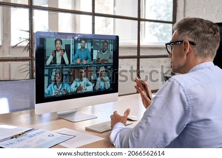 Corporate leader manager leading videoconference with diverse team business people having digital group video call conference working in office at online virtual meeting on pc computer. Over shoulder Royalty-Free Stock Photo #2066562614