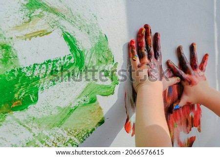 close-up of children's hands in paint.Bright multi-colored paint on the hands. boy or girl draws on the wall with his hands.Children's creativity. Develop motor skills,fantasy,imagination. copy space Royalty-Free Stock Photo #2066576615