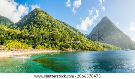 Caribbean beach with palms and straw umrellas on the shore with Gros Piton mountain in the background, Sugar beach, Saint  Lucia Royalty-Free Stock Photo #2066578475