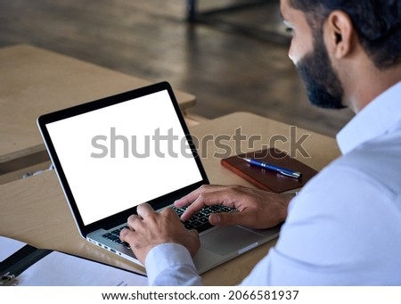 Over shoulder closeup view of male indian businessman looking at empty blank mockup screen for advertising, working, typing, planning, analyzing data. Business technologies concept. Royalty-Free Stock Photo #2066581937