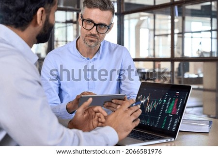Diverse managers traders analysts discussing financial growth market at desk with laptop with graphs on screen using tablet device. Investors brokers analysing indexes online cryptocurrency stock. Royalty-Free Stock Photo #2066581976