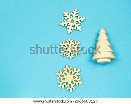 wooden natural Christmas tree and wooden snowflakes .blue background.