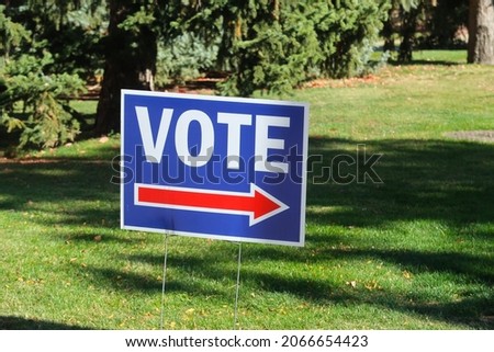 Red, white and blue sign directing people to vote