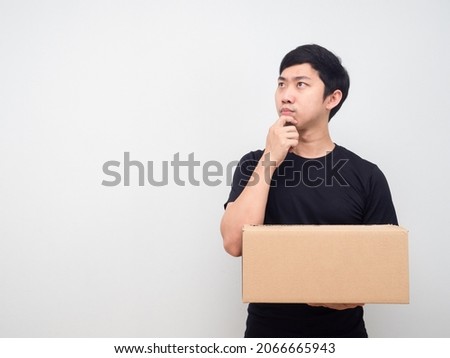 Man black shirt holding parcel box looking at copy space and thinking something