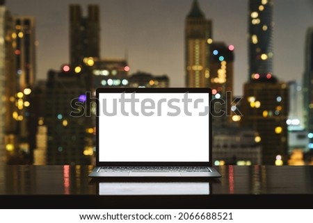 laptop computer on workspace white blank screen display city on night background Royalty-Free Stock Photo #2066688521