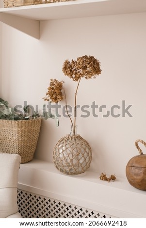 Scandinavian decor as a decoration in the house. Dried hydrangea flowers in a vase, eucalyptus branches in a wicker basket on a shelf in the living room or bedroom