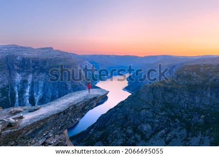 Alone tourist on Trolltunga rock - most spectacular and famous scenic cliff in Norway - Landscape Royalty-Free Stock Photo #2066695055