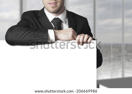 businessman in black suit leaning on blank white sign
