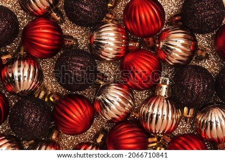 Luxury Christmas decorative composition with golden and red christmas balls on gold shiny background. Christmas or New Year concept. Festive background with baubles and copy space                     