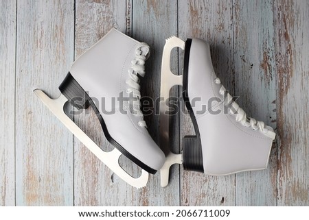 White ice skates for figure skating on a colored wooden surface. Winter sport concept. Top view, flat lay.