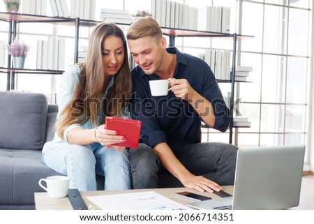 Male and female couple sitting at a desk and use a laptop computer 