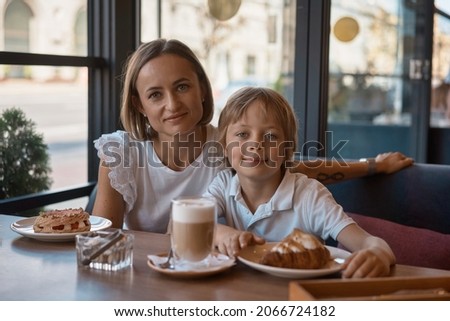 Mother and son having lunch in sidewalk restaurant.Mom and son eat a croissant in a cafe.