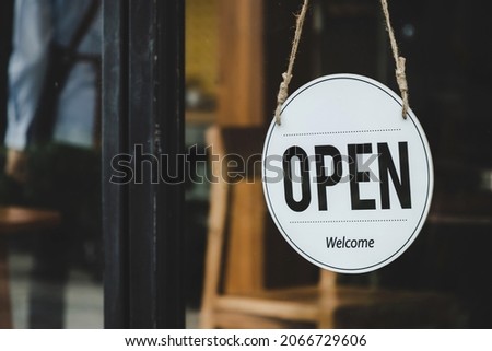 Welcome. vintage wooden OPEN sign board hanging on glass door in modern cafe restaurant, reopening cafe restaurant, retail store, small business owner, takeaway food, food and drink concept 
