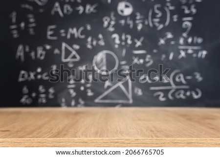 Education concept - empty wooden table and chalkboard background for product display