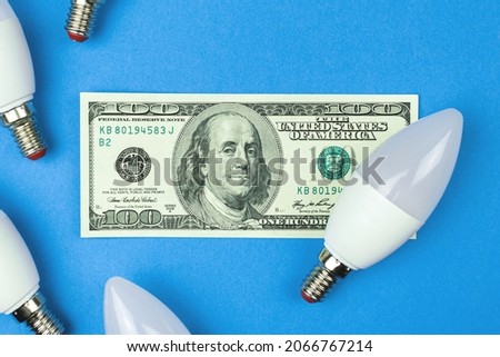 Electricity costs. LED light bulbs and money, dollar bills. Energy savings, energy efficiency concept 
