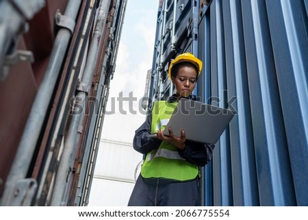 Young African American woman worker at overseas shipping container yard . Logistics supply chain management and international goods export concept . Royalty-Free Stock Photo #2066775554