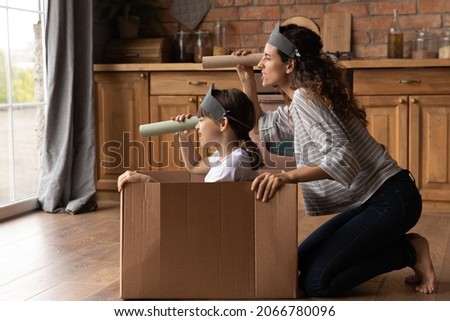 Happy creative mother and active daughter girl playing pirates ship at home, sailing carton box boat, looking forward through toy paper spyglasses, enjoying home activities. Family role game Royalty-Free Stock Photo #2066780096