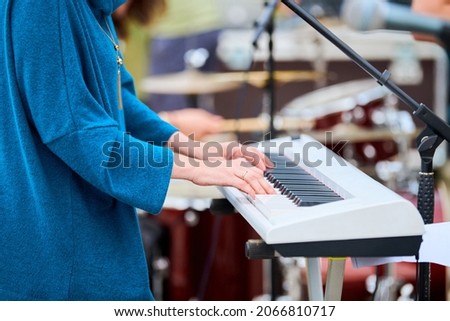 Musician woman playing on white synthesizer keyboard piano keys, female hands on synthesizer, close up. Musician playing synthesizer on concert stage, professional playing on synth piano Royalty-Free Stock Photo #2066810717
