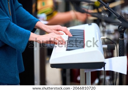 Musician woman playing on white synthesizer keyboard piano keys, focus on female hands on synthesizer. Musician playing musical instrument on concert stage, cropped image of person playing synthesizer Royalty-Free Stock Photo #2066810720