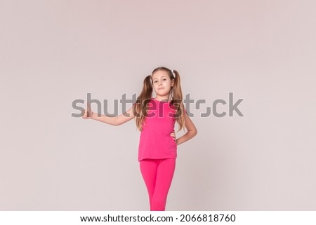 a sporty beautiful girl with tails in pink clothes shows her finger up. on isolated white background. Copy space