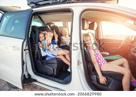 Group of four cute adorable little happy caucasian children enjoy having fun sit in minivan going to sea beach road trip on hot summer day. Kids in swimsuit in car with side open door against sun Royalty-Free Stock Photo #2066829980