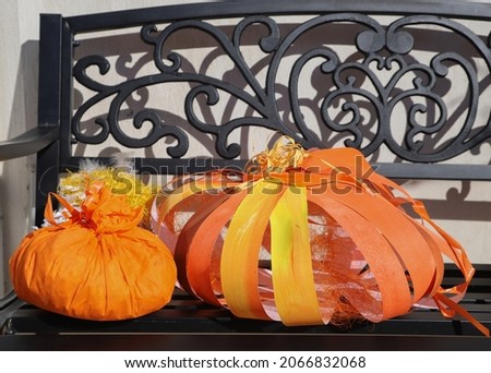 Closeup picture of decorative orange pumpkins made of paper in a sunny garden