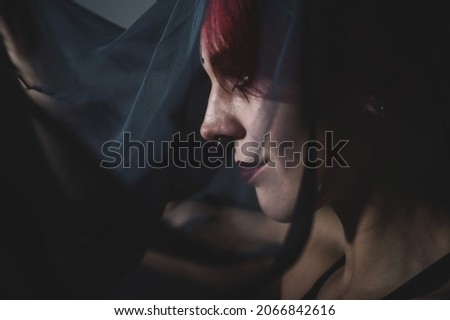 Profile of a woman in a black veil. Costume Dead bride for Halloween. Portrait of an evil grinning Witch in front of a coven.
