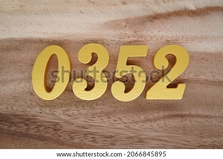 Golden Arabic numerals 0352 on a dark brown to white wood grain background.