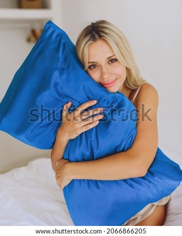 European blonde on the bed hugs a pillow with a silk pillowcase.
 Royalty-Free Stock Photo #2066866205