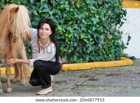 beautiful girl with chestnut pony posing together near green wall