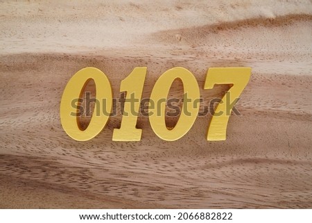 Golden Arabic numerals 0107 on a dark brown to white wood grain background.