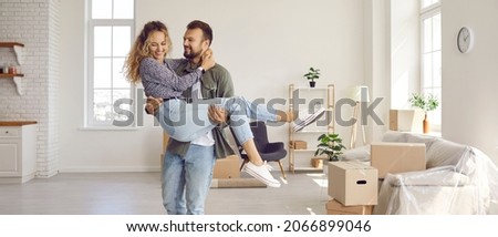 Joyful couple moves to their own first home. Happy loving husband holding his beloved wife in his arms in their new house during move. Property buying or mortgage concept. Banner. Royalty-Free Stock Photo #2066899046