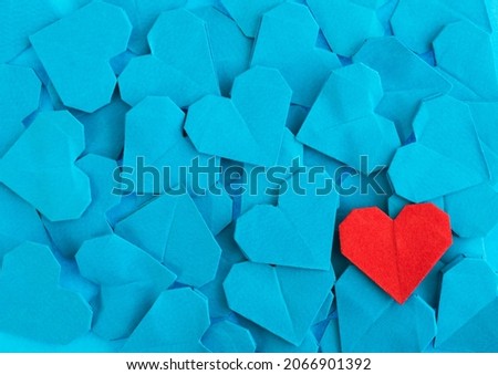 Red origami heart on blue origami hearts.