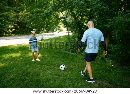 Father and son play football on the grass outdoors