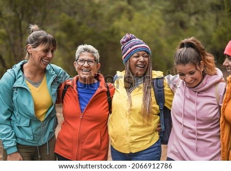 Happy multiracial women having fun embracing each other on trekking day outdoor - Healthy lifestyle and multi generational friendship concept