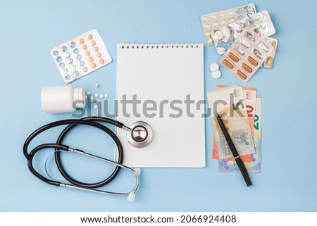 Cost of medicinal products, treatment concept. Top view. Cost of health care with EURO bank notes, stethoscope, notebook, medicaments. Price of medicine. Medical expenses. EURO small bills cash money