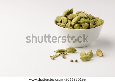 Fragrant oriental spices cardamom pods with seeds in a small white ceramic boul with copy space Royalty-Free Stock Photo #2066950166
