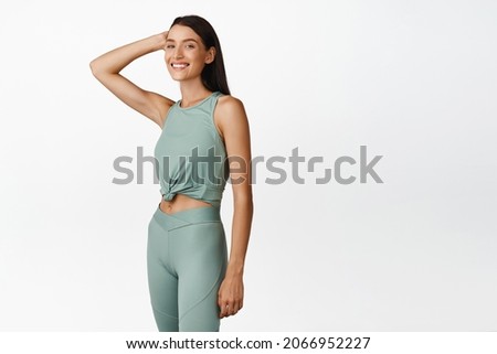 Full length young healthy fitness woman with fit body, wearing sport leggings, smiling and looking at camera. concept of workout and gym