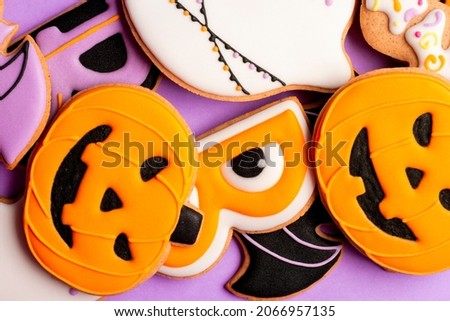 Homemade Halloween cookies, pumpkins, ghosts, bats on purple background.