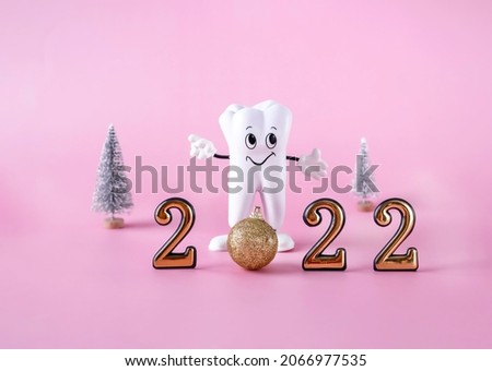 cartoon model of a tooth, a Christmas ball, figures of the new year 2022 on a pink background