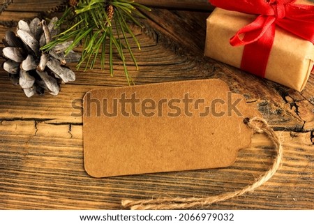craft tag on a wooden background next to a spruce branch and a gift, the concept of the new year, congratulations.