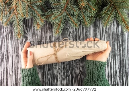 Wine bottle wrapped in kraft paper. Christmas present. Woman holding a gift. Royalty-Free Stock Photo #2066997992