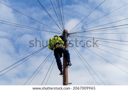 Telecommunications, telecom engineer at work on the top of a telegraph pole Royalty-Free Stock Photo #2067009965