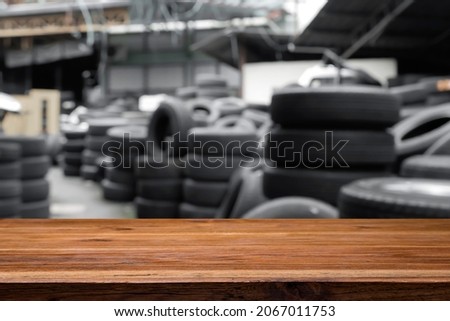 Empty wooden table space platform and blurred tire shop or old tire storage background for product display montage.